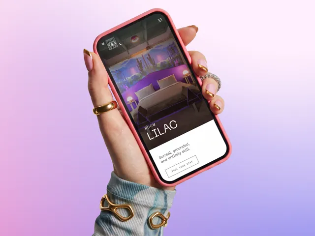 The Maison Lézard room page open on a phone, held against a lilac backdrop
